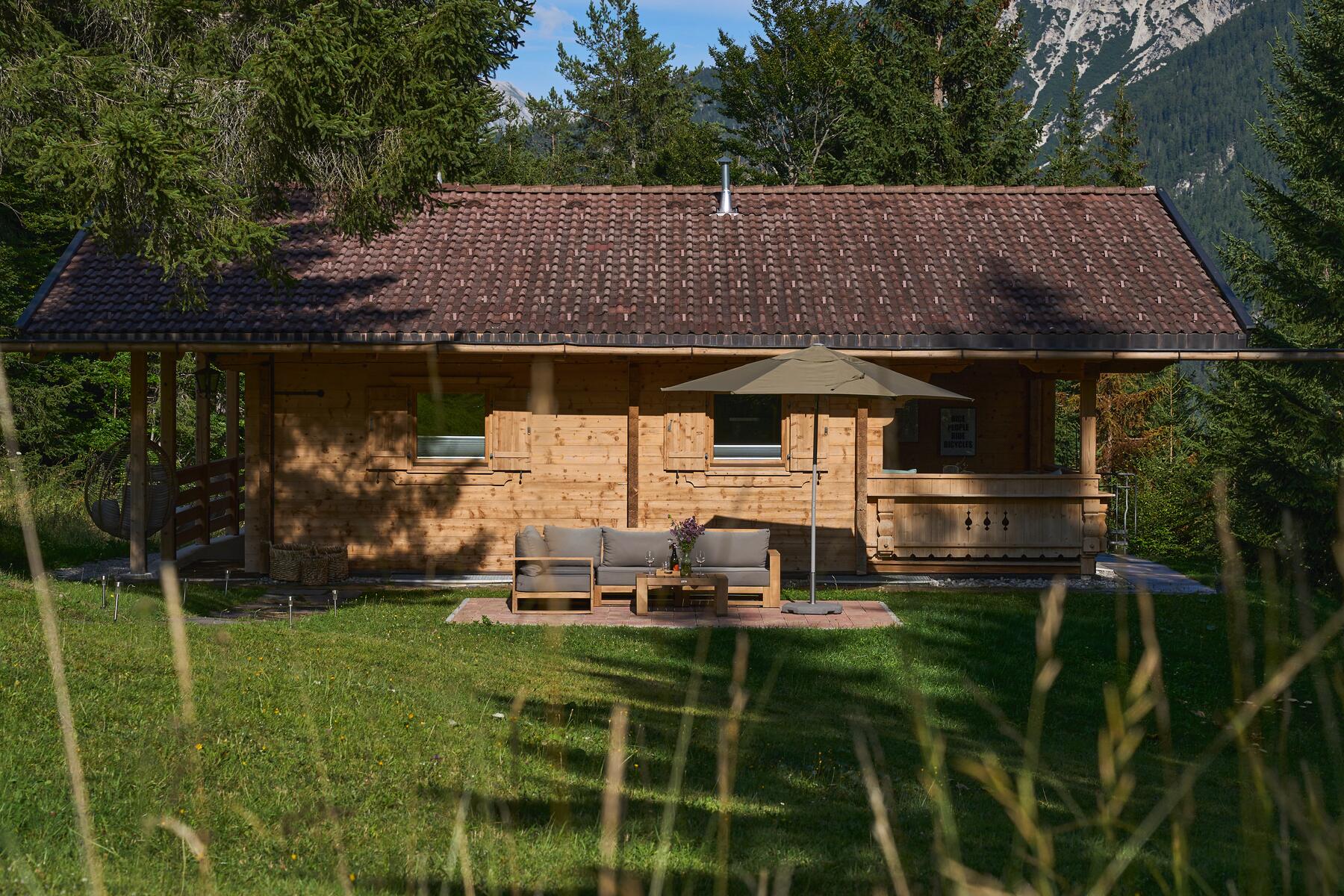 mei chalet - DAS BARBARA Das Chalet mei chalet DAS BARBARA im Sommer mit Lounge-Terrasse auf der Wiese am Waldrand
